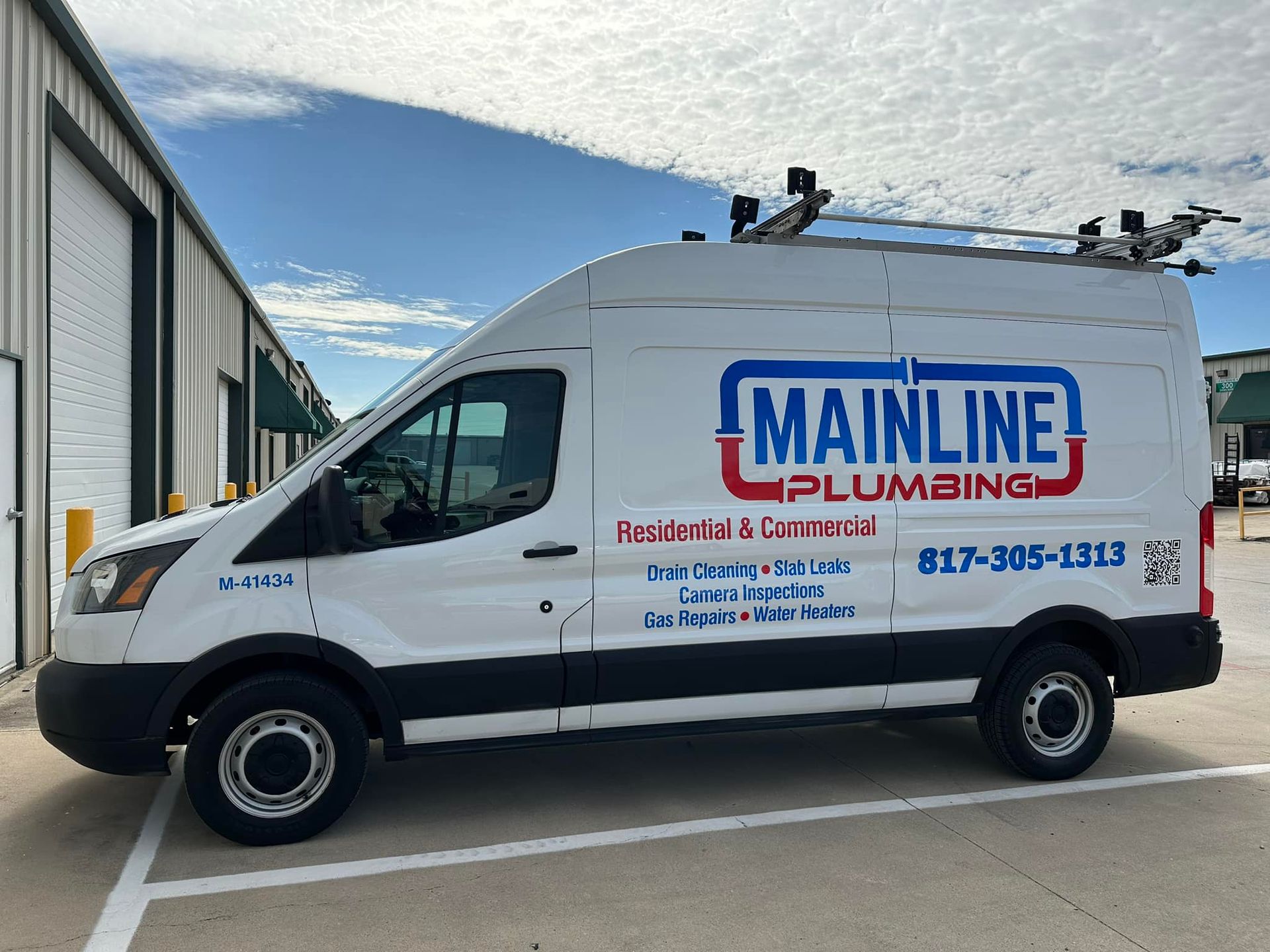 A white mainline plumbing van is parked in a parking lot