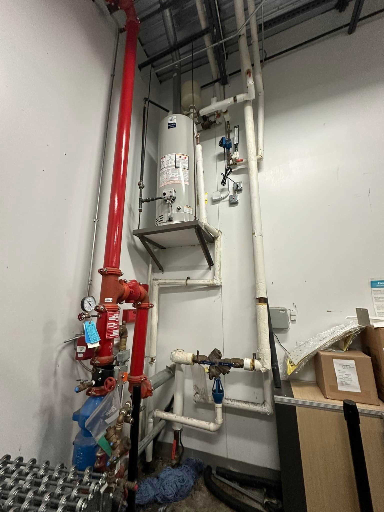 A room with a lot of pipes and a water heater.