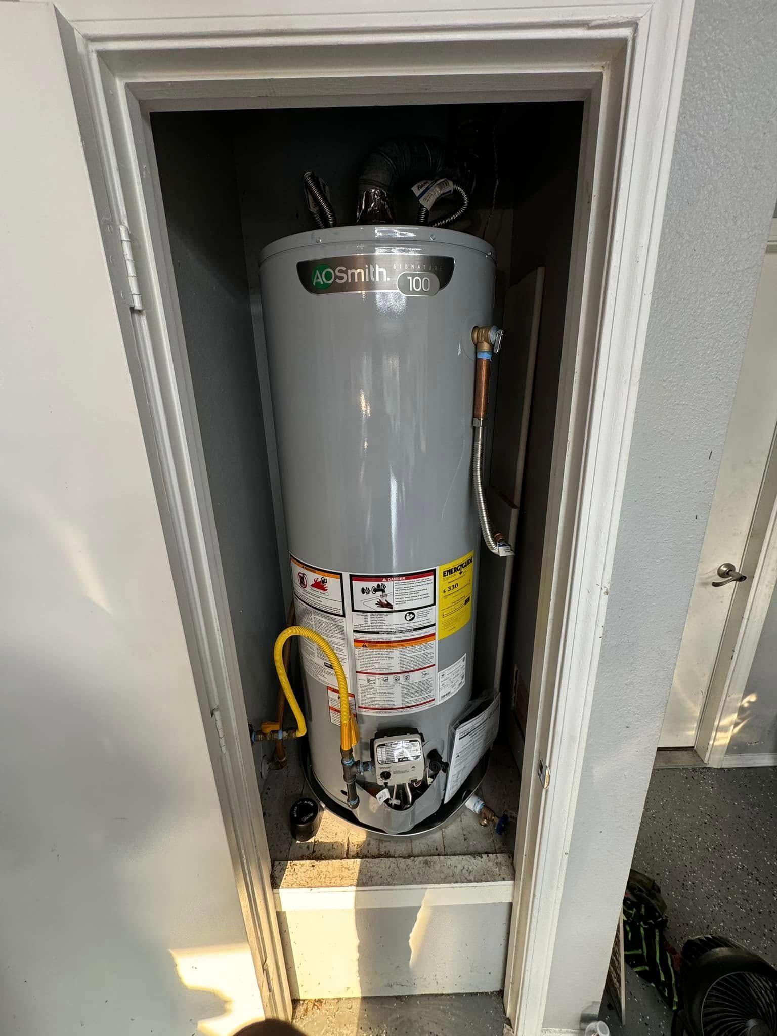 A gas water heater is sitting in a closet.