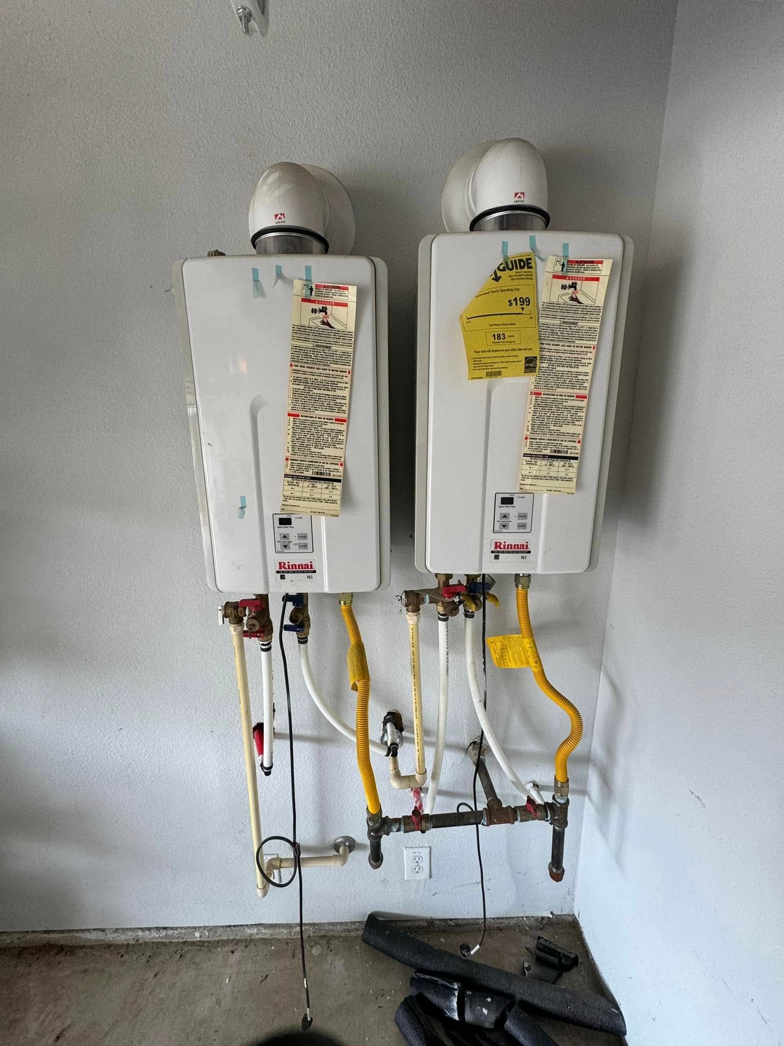 Two water heaters are hanging on the wall in a room.