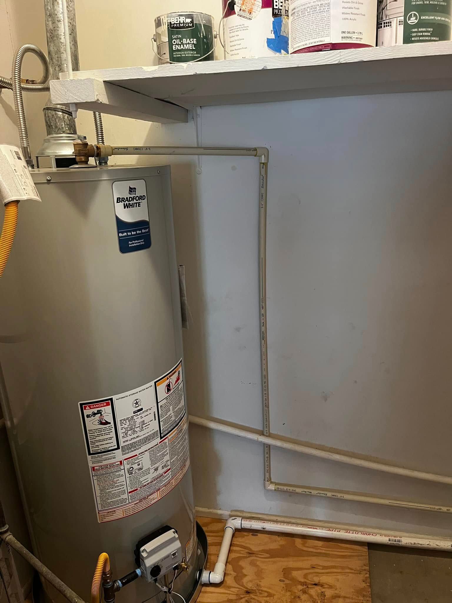 A water heater is sitting in a laundry room next to a shelf.