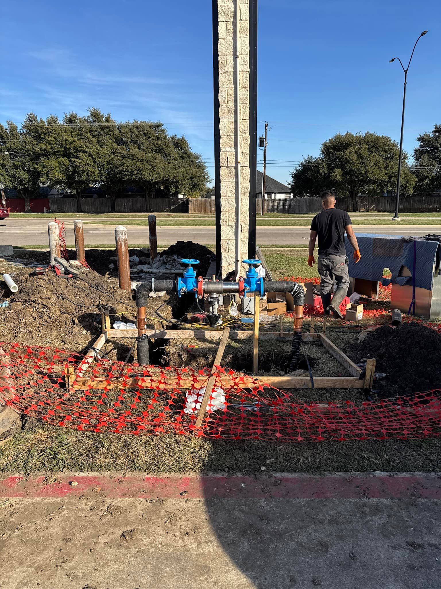 A man is standing in the dirt in front of a building under construction.