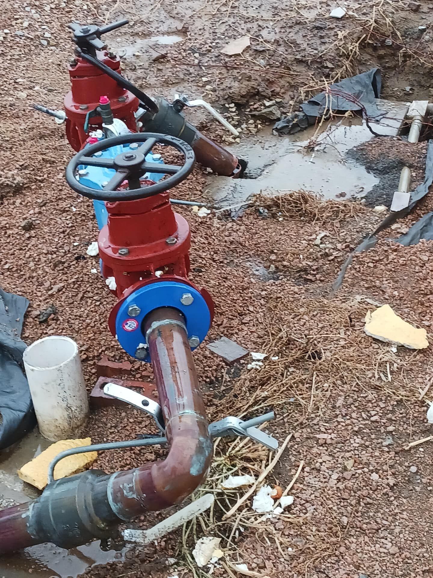 A bunch of pipes and valves are laying on the ground.