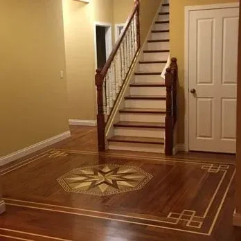 A hallway with a staircase and a wooden floor.