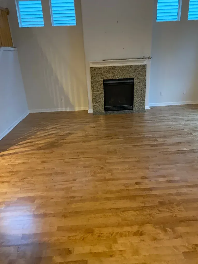 An empty living room with hardwood floors and a fireplace.