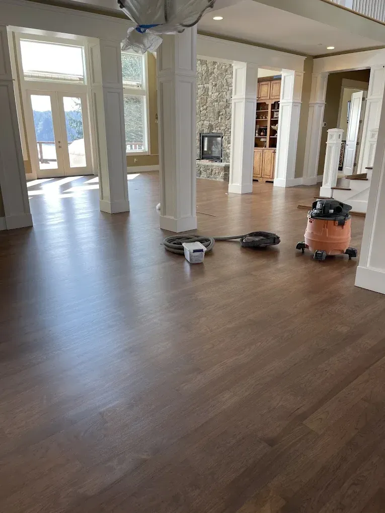 A vacuum cleaner is sitting on a wooden floor in a living room.