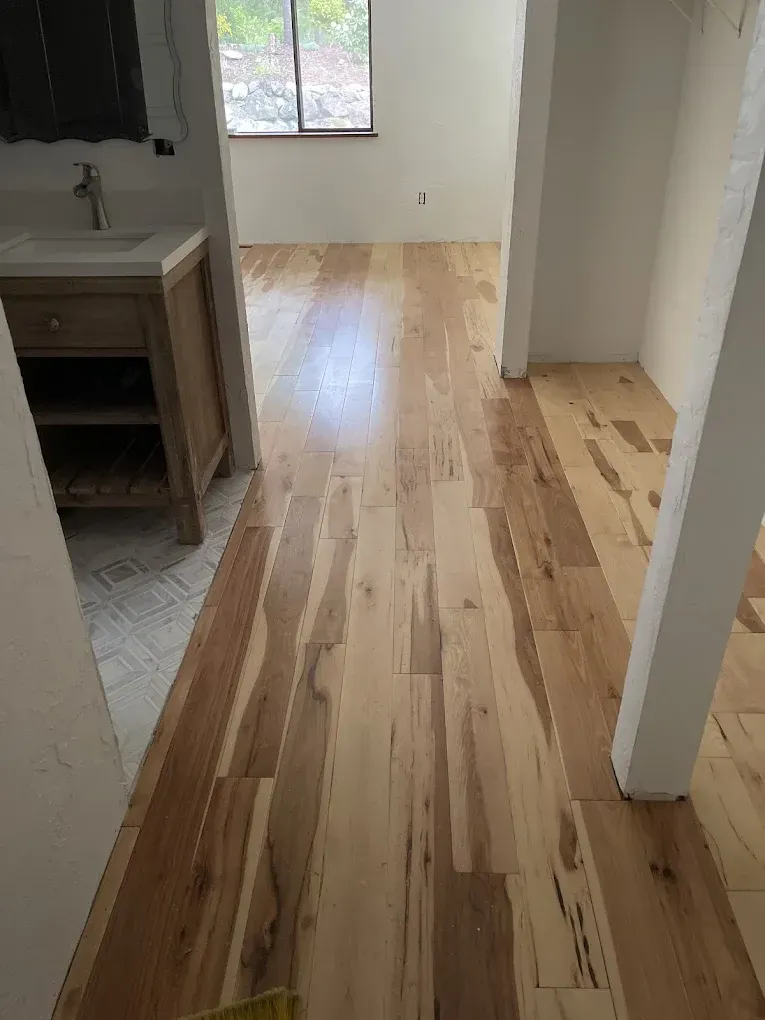 A wooden floor in a room with a sink and a window.