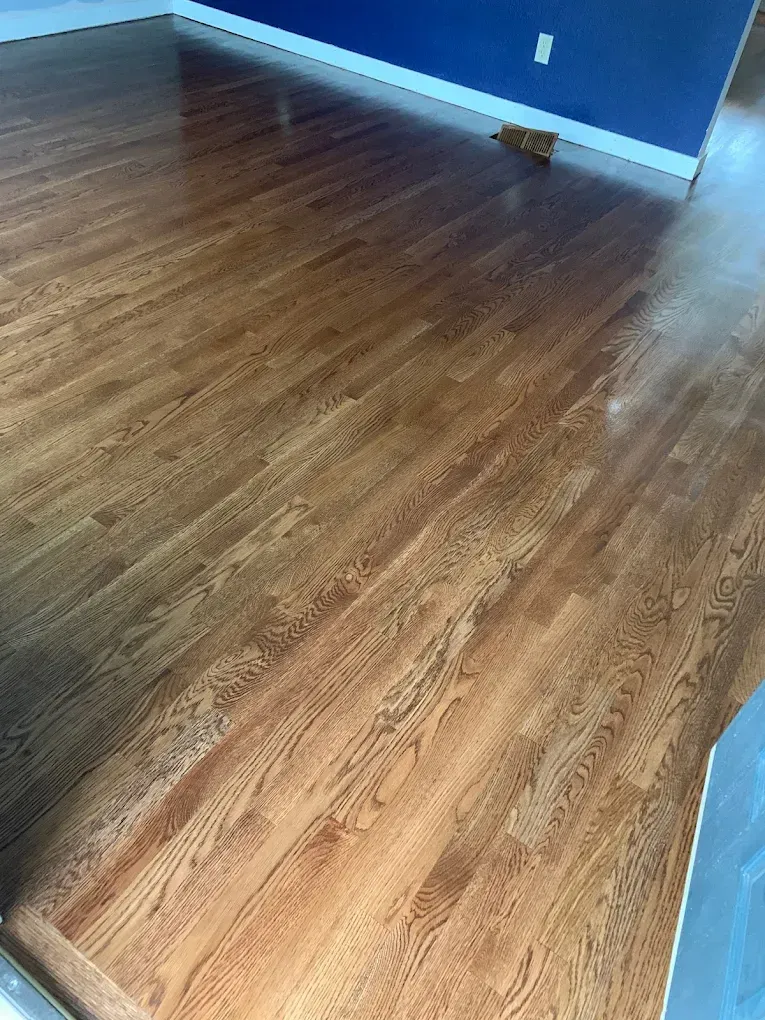 A wooden floor in a living room with a blue wall.