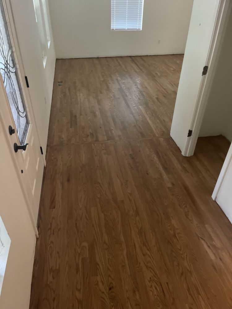 A hallway with hardwood floors and a window in a house.