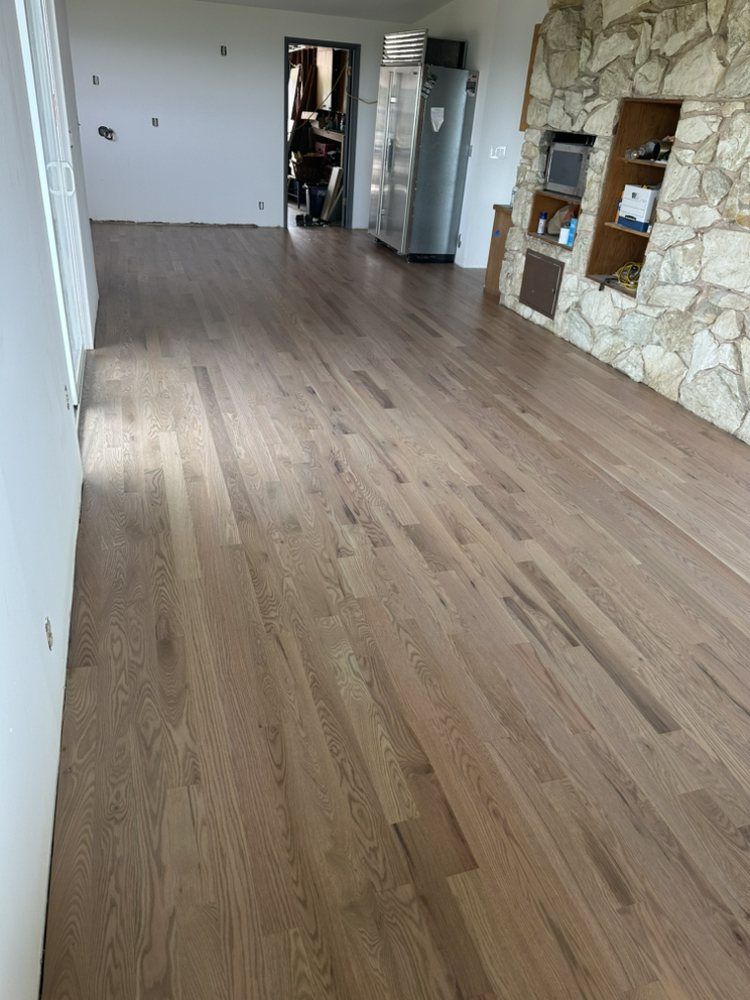 A living room with hardwood floors and a stone fireplace.