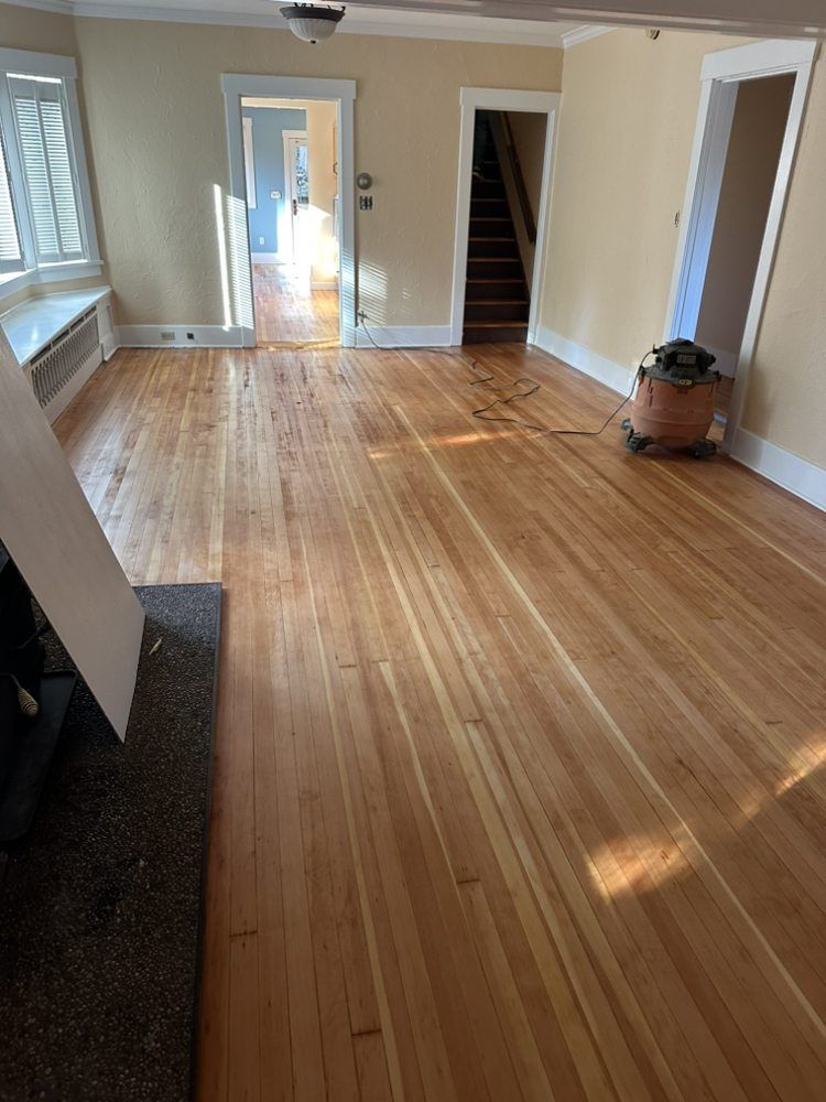 A living room with hardwood floors and a vacuum cleaner on the floor.