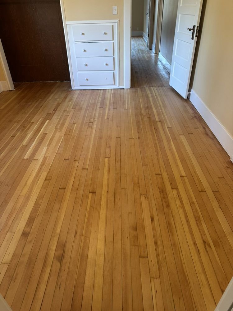 A bedroom with hardwood floors and a dresser.