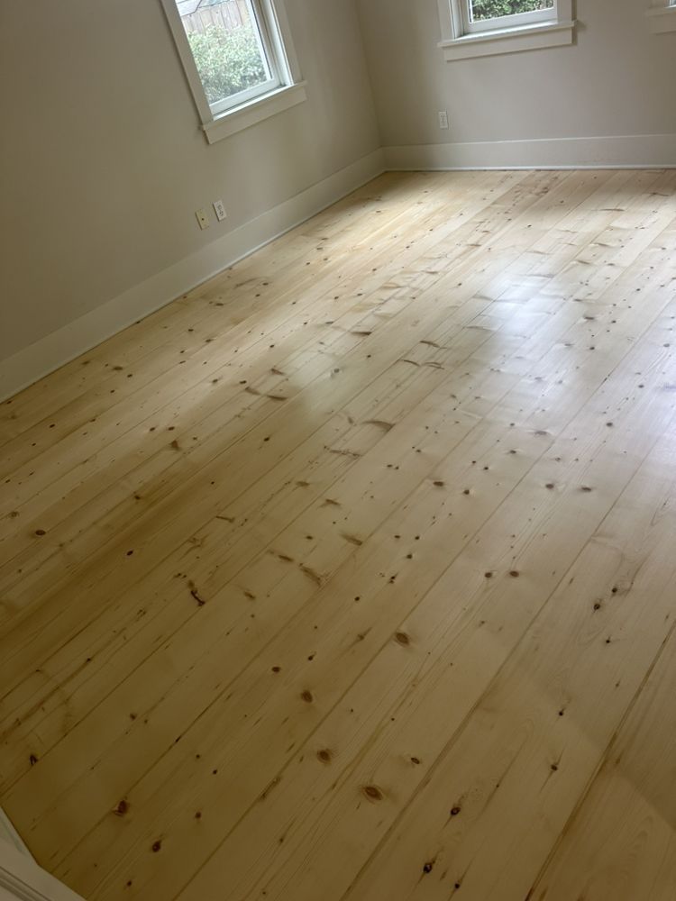 A room with a wooden floor and two windows.