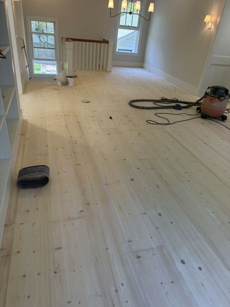 A vacuum cleaner is sitting on a wooden floor in a living room.