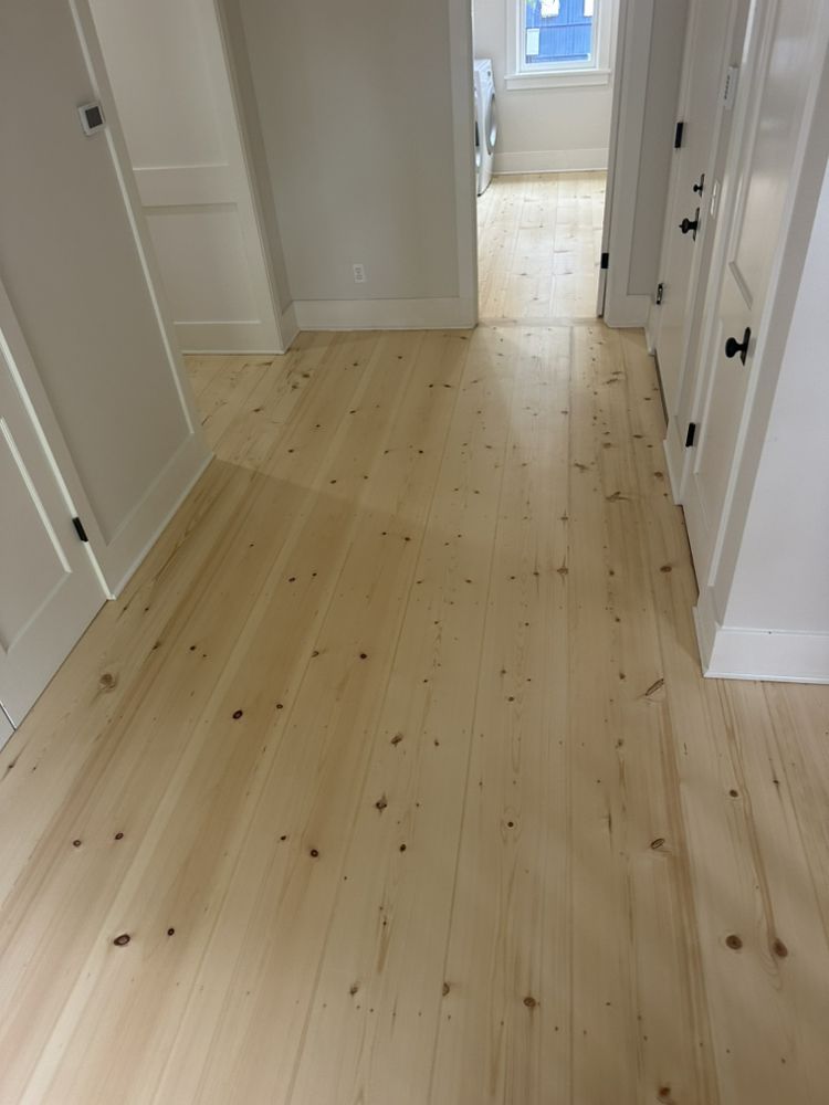 A hallway with a wooden floor and white doors