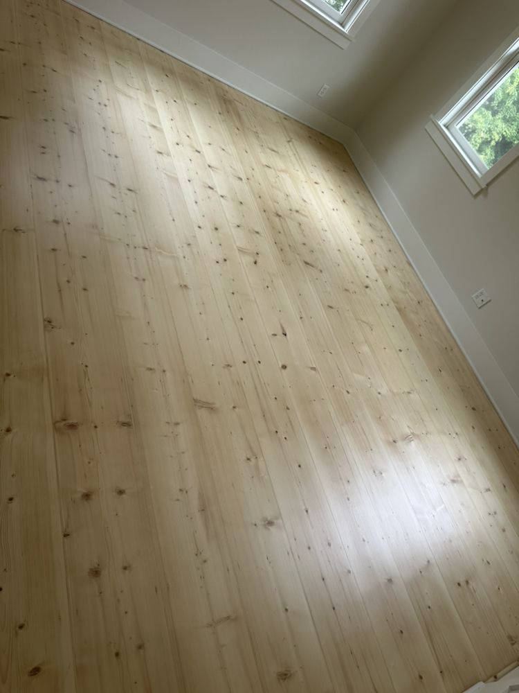 A room with a wooden floor and two windows.