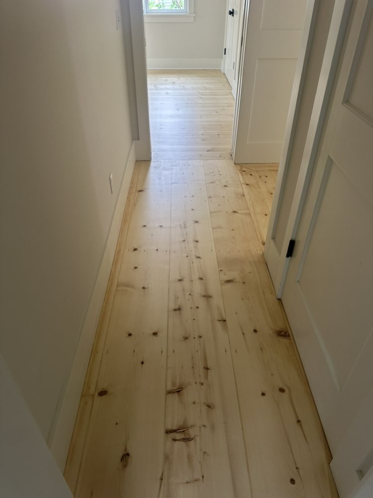 A hallway with wooden floors and white walls in a house.