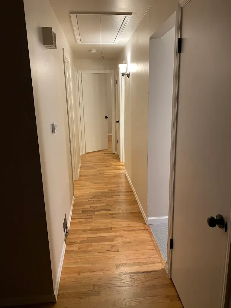 A long hallway with wooden floors and white walls.