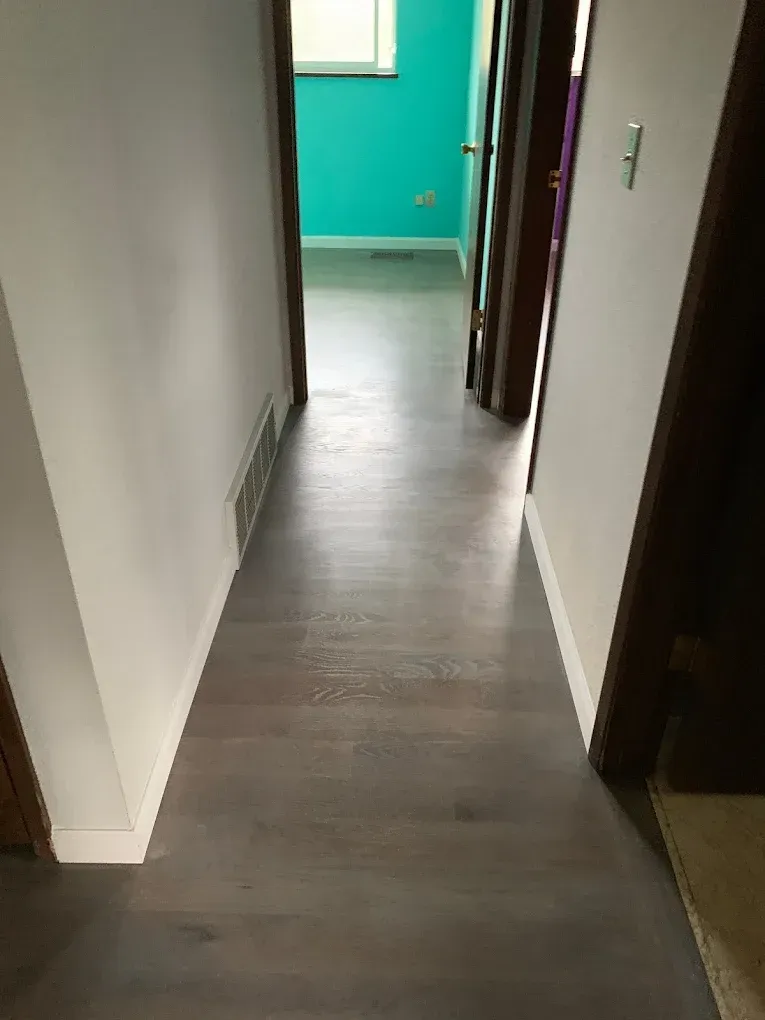A hallway with hardwood floors and a blue wall.