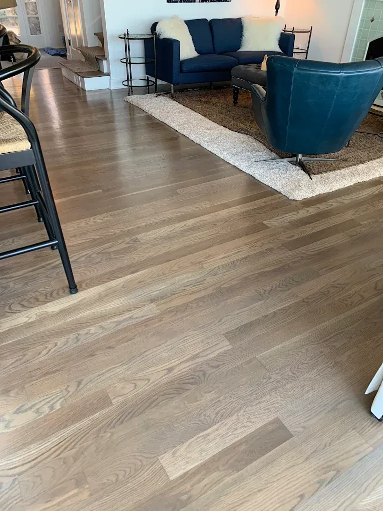A living room with hardwood floors , a couch , chairs , and a rug.