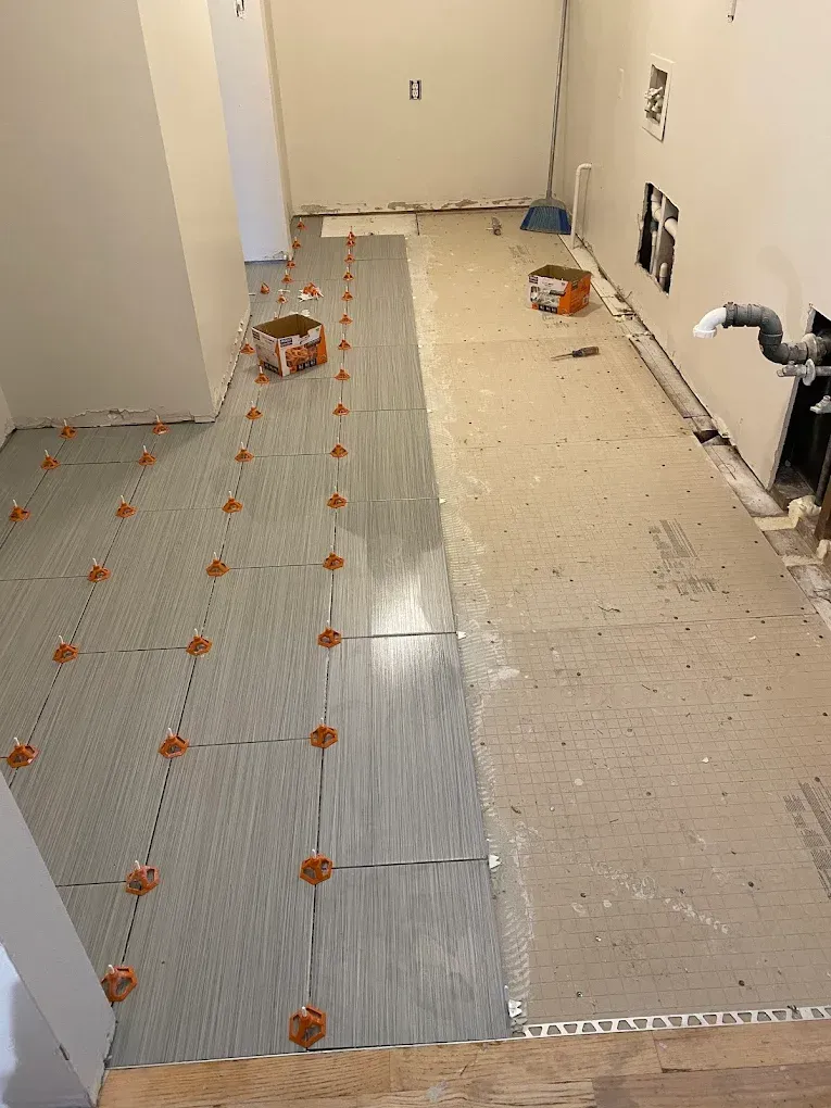 A bathroom under construction with tiles being installed on the floor.