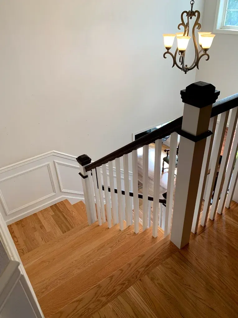 A wooden staircase with a white railing and a chandelier hanging from the ceiling.