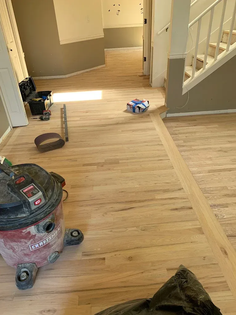 A vacuum cleaner is sitting on a wooden floor in a room next to a staircase.