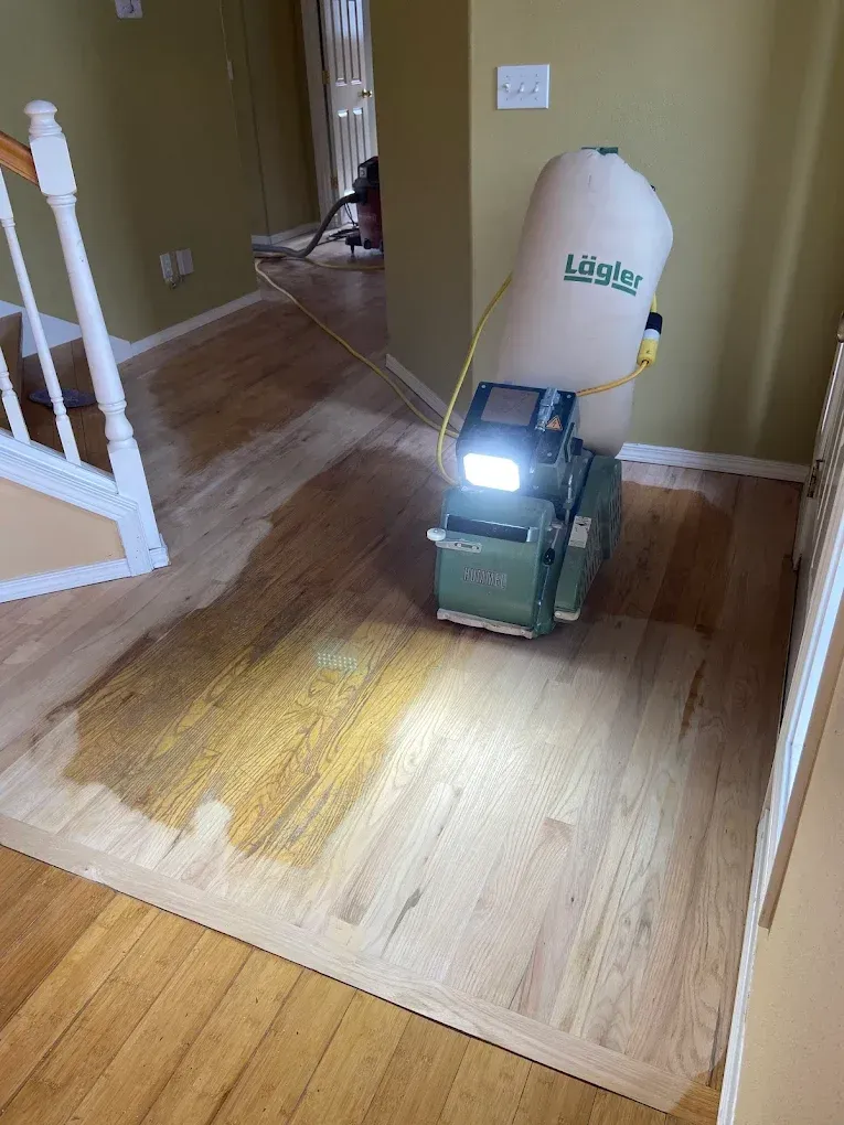 A machine is sanding a hardwood floor in a living room.