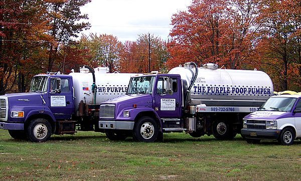 A circular concrete ring set into a pit of freshly dug soil in a garden, with lush green banana trees in the background.