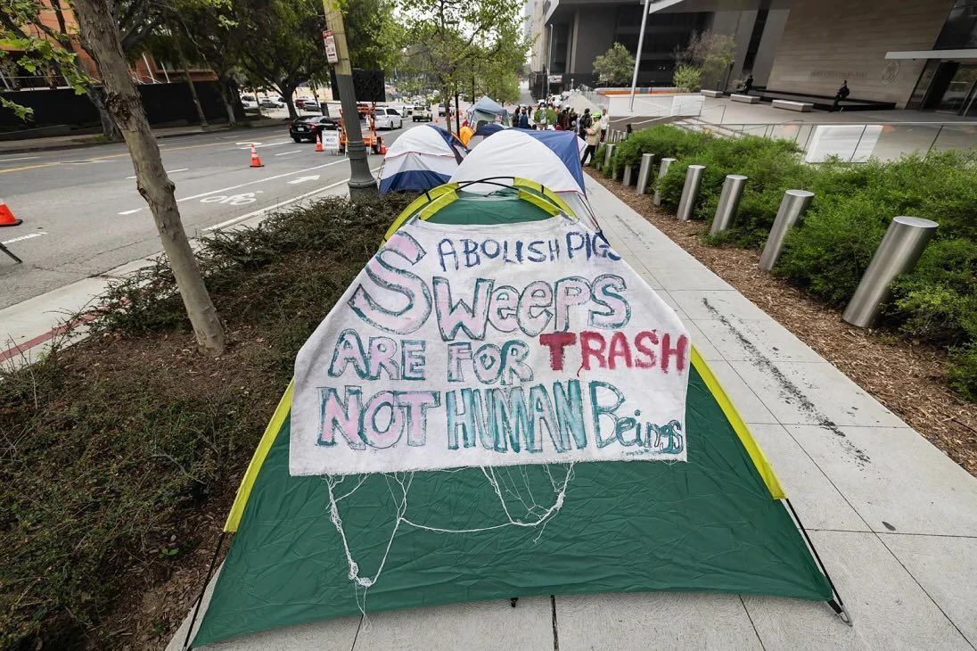A tent on a sidewalk with a sign reading 
