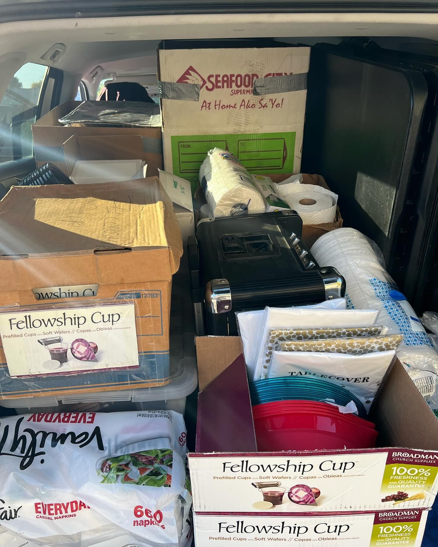 The trunk of a vehicle packed with stacked cardboard boxes, including several marked 