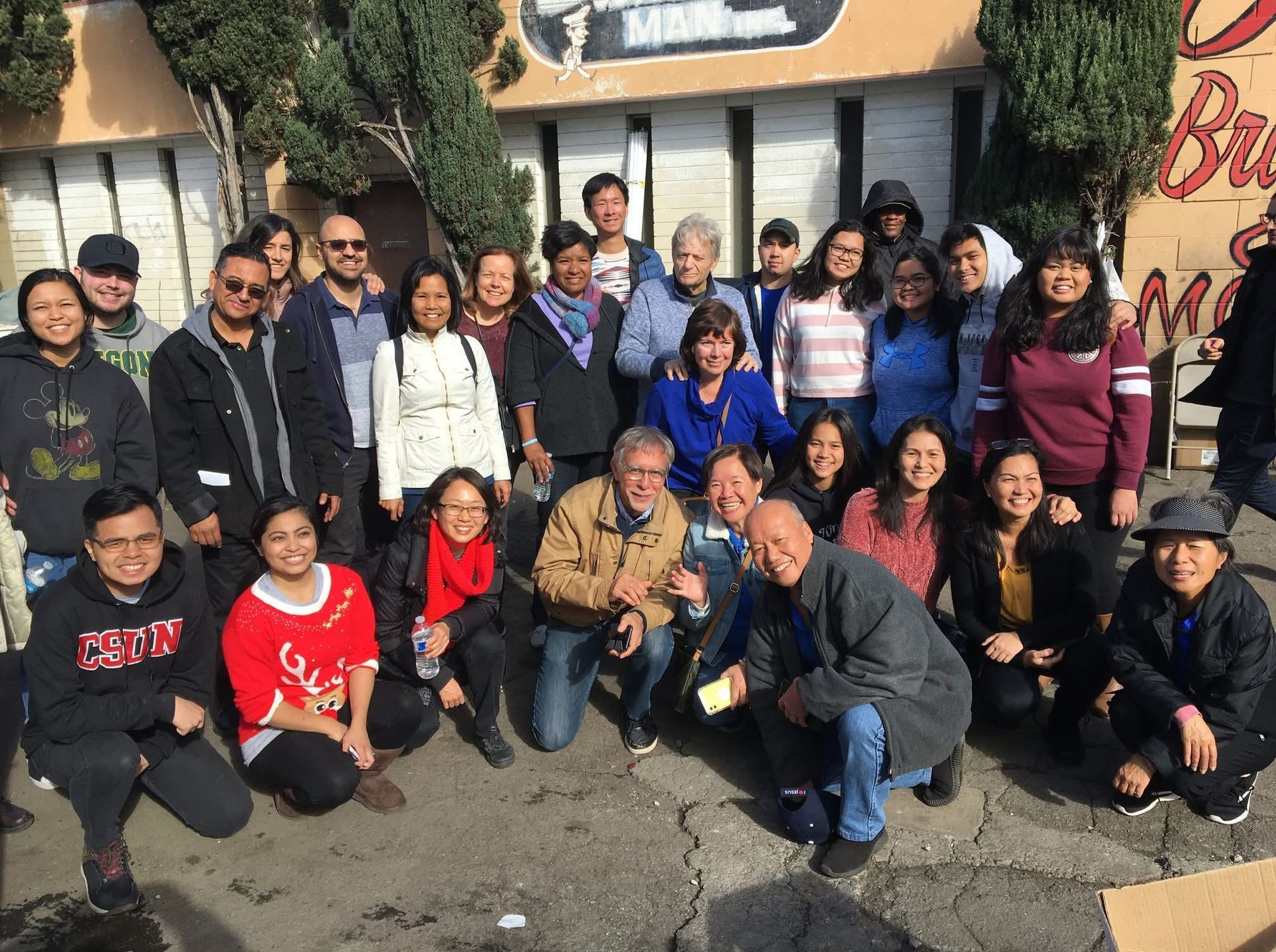 A diverse group of people posing for a photo outdoors in front of a building.