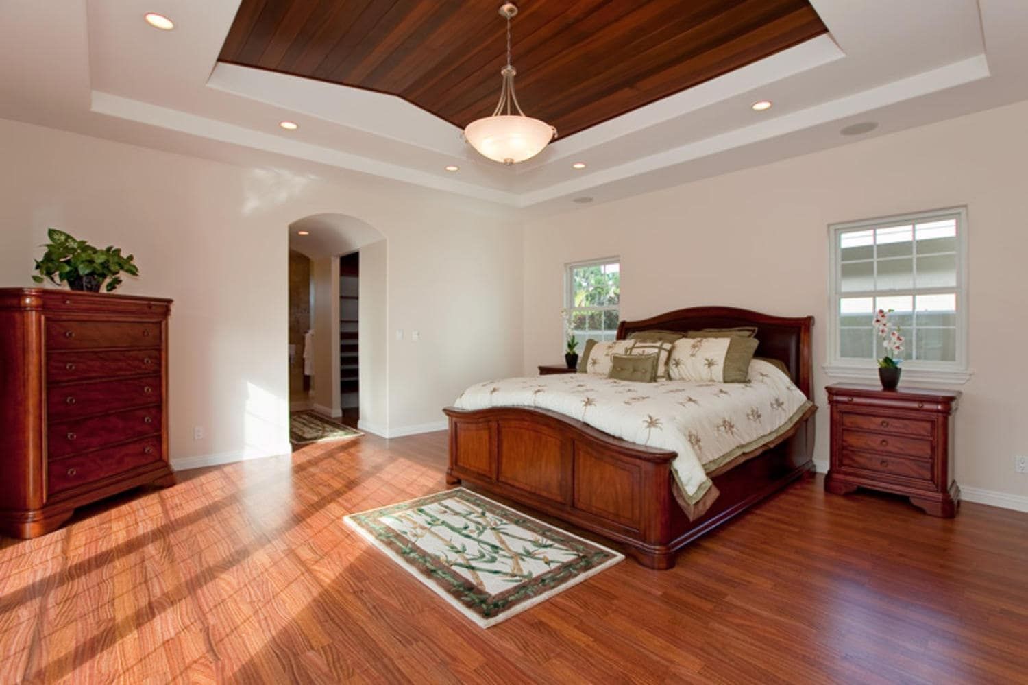 Bedroom with hardwood floors, dark wood furniture, and a decorative ceiling.