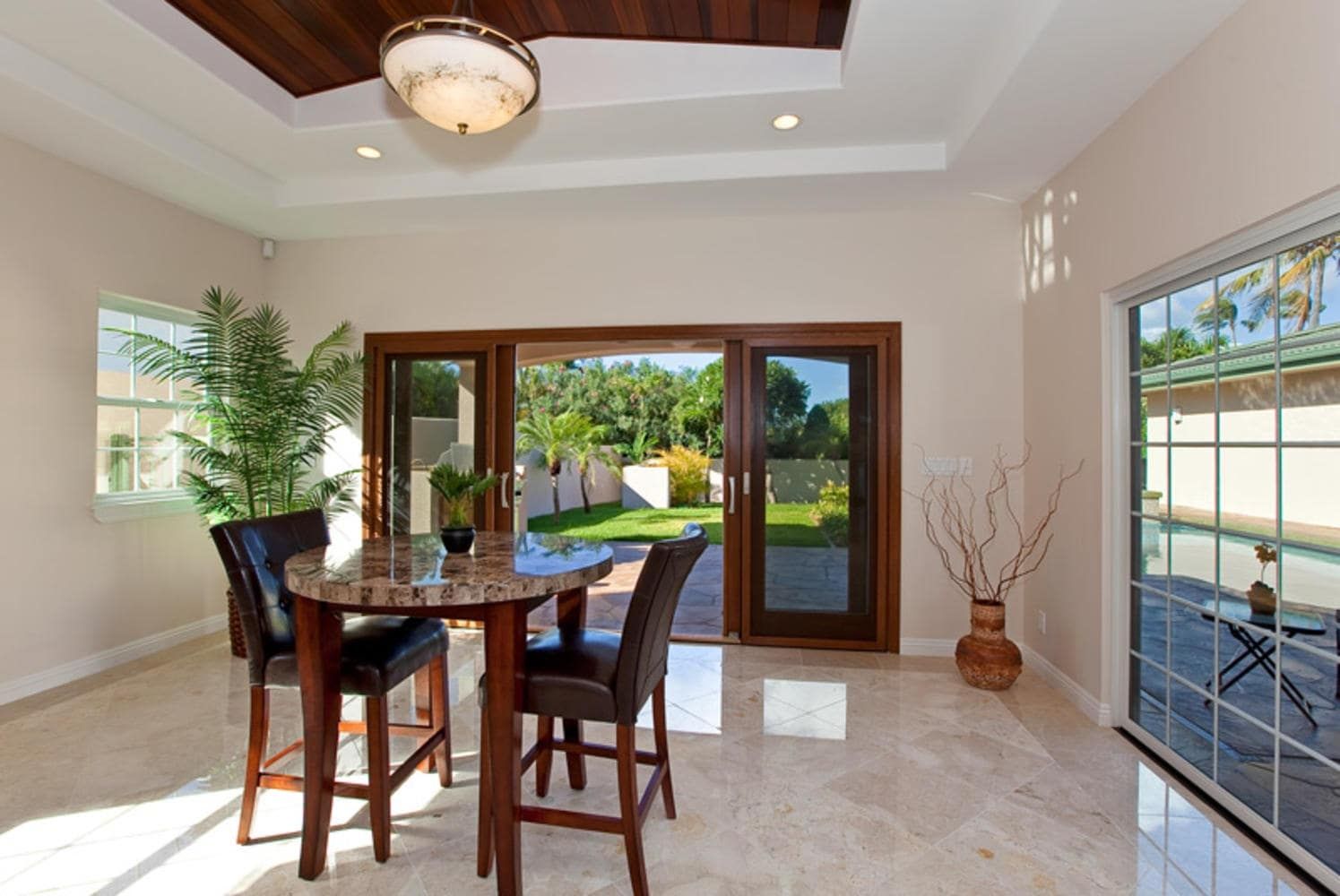 Dining area with a round table, chairs, and doors leading to a backyard.