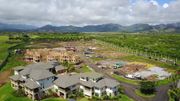Aerial view of houses under construction with a mountainous backdrop and green landscape.