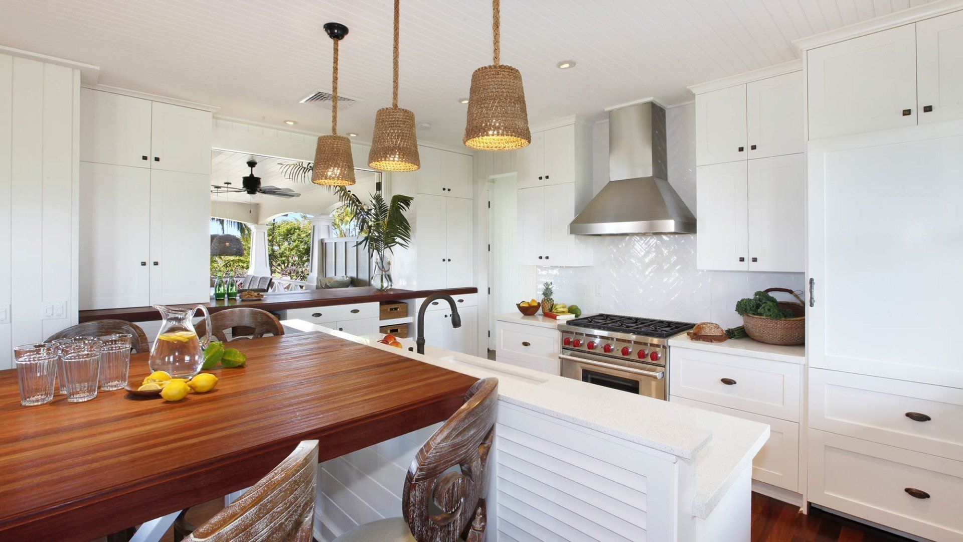 Kitchen with white cabinets, wooden island, stainless steel appliances, and pendant lights.