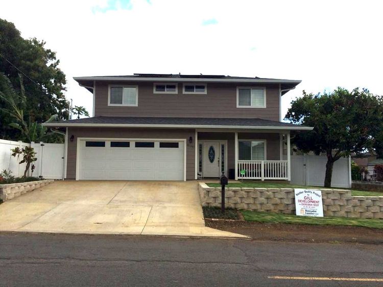 Two-story house with brown siding, white garage door, and a small front porch, gray roof.