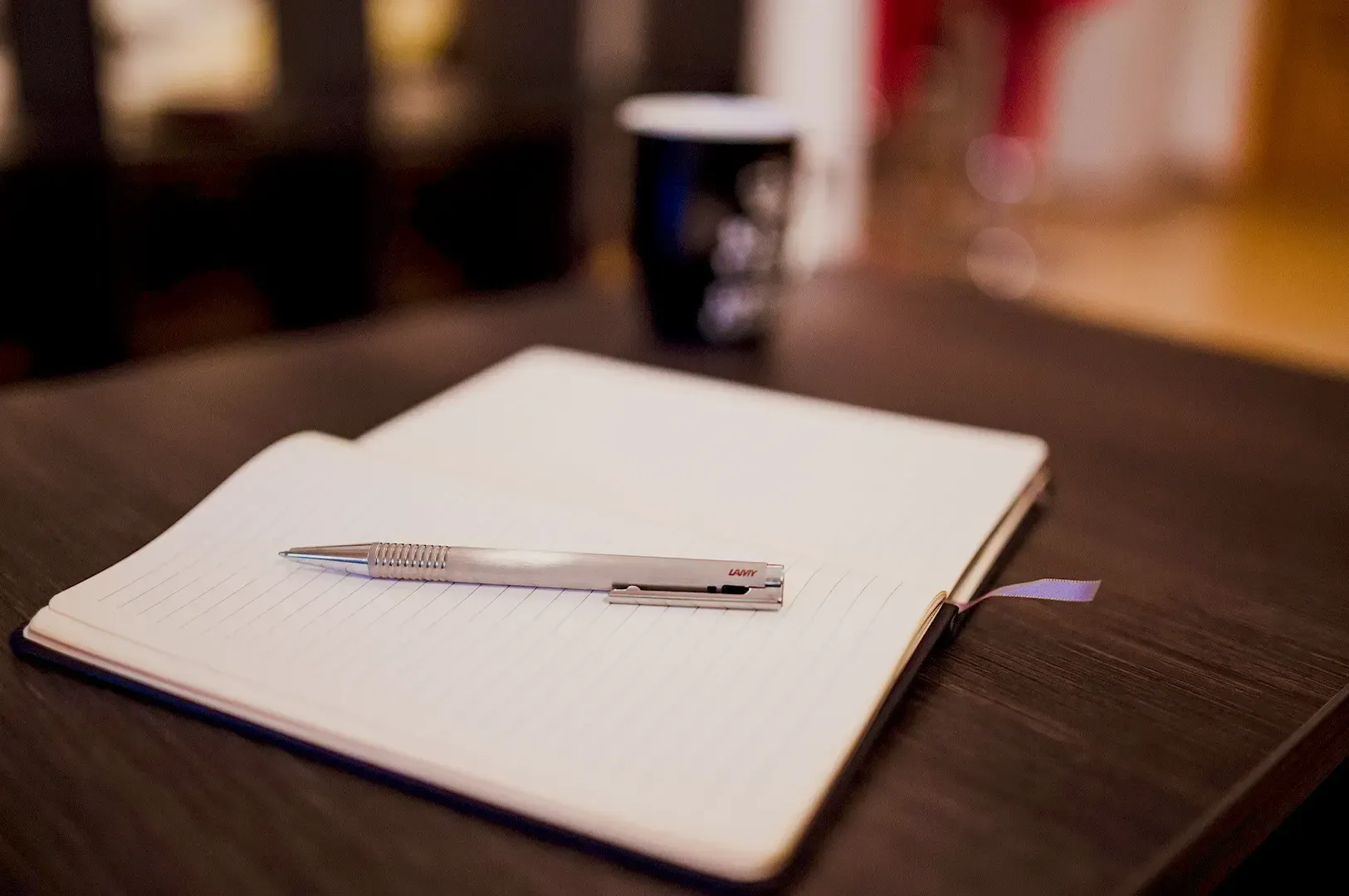 A notebook and pen resting on a dark desk, symbolizing the reflective and intentional planning requi