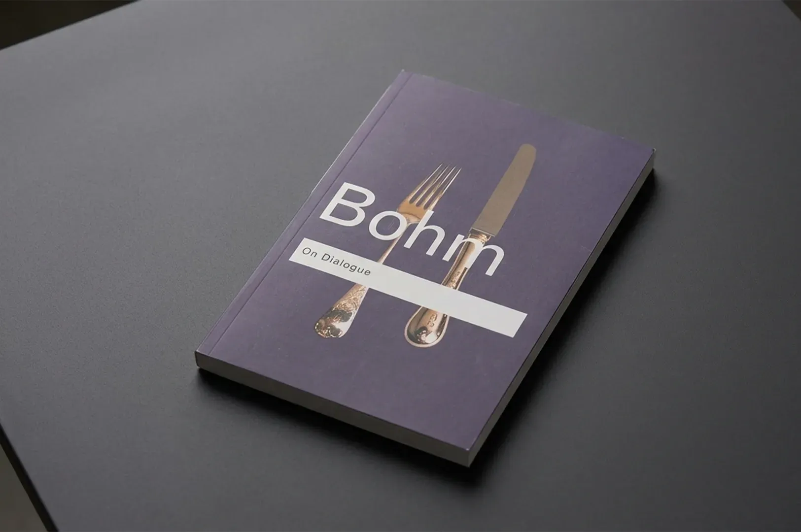 A copy of 'On Dialogue' by David Bohm resting on a dark surface, representing the foundational conce