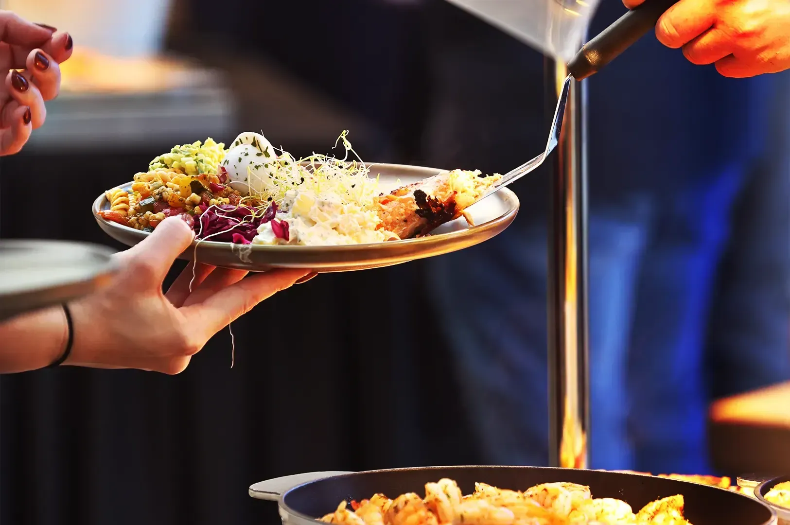 A close-up view of a person being served a variety of colorful dishes from a buffet line, illustrati