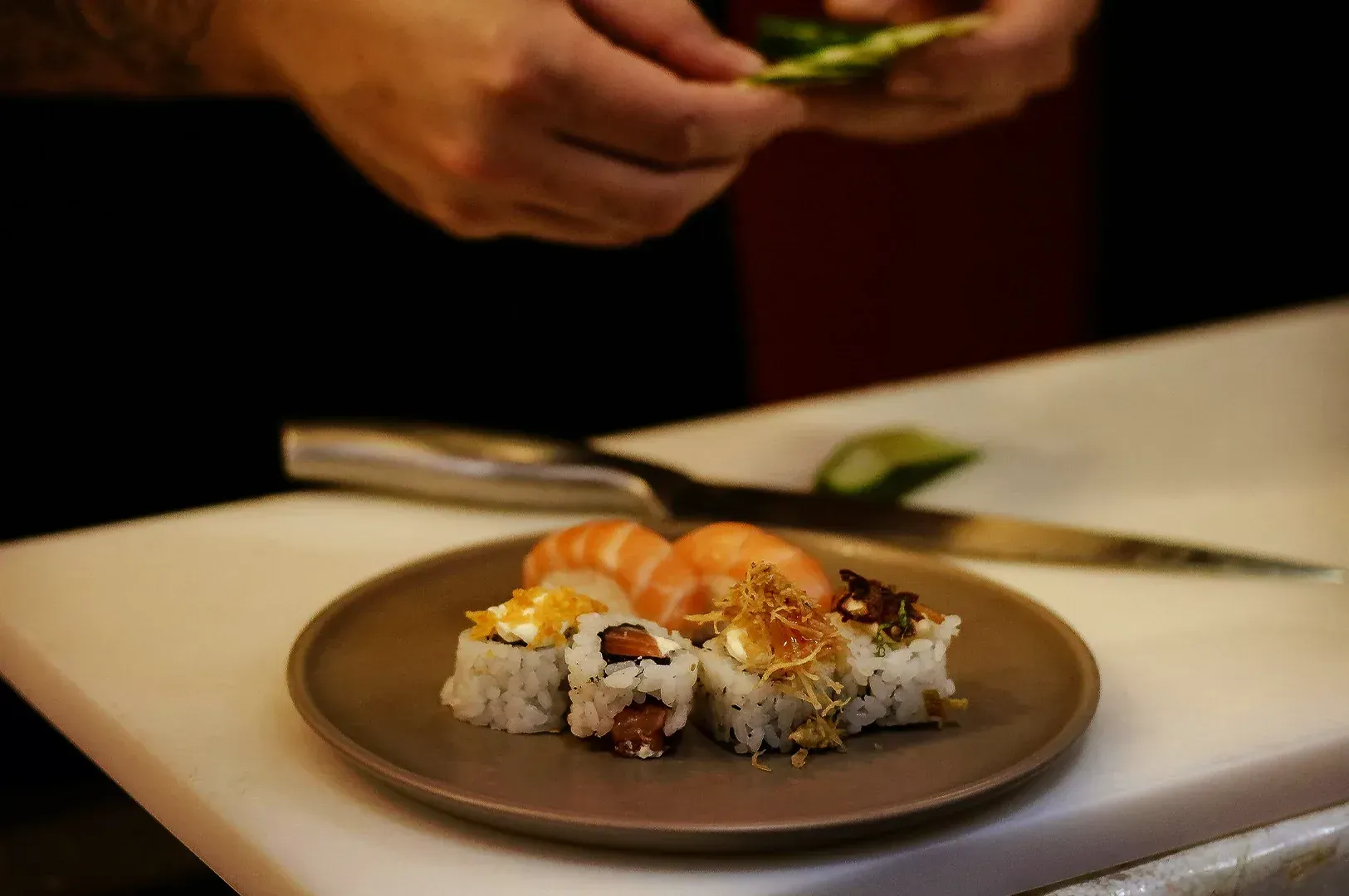 A chef's hands meticulously preparing sushi, representing the deliberate rituals of decision-making