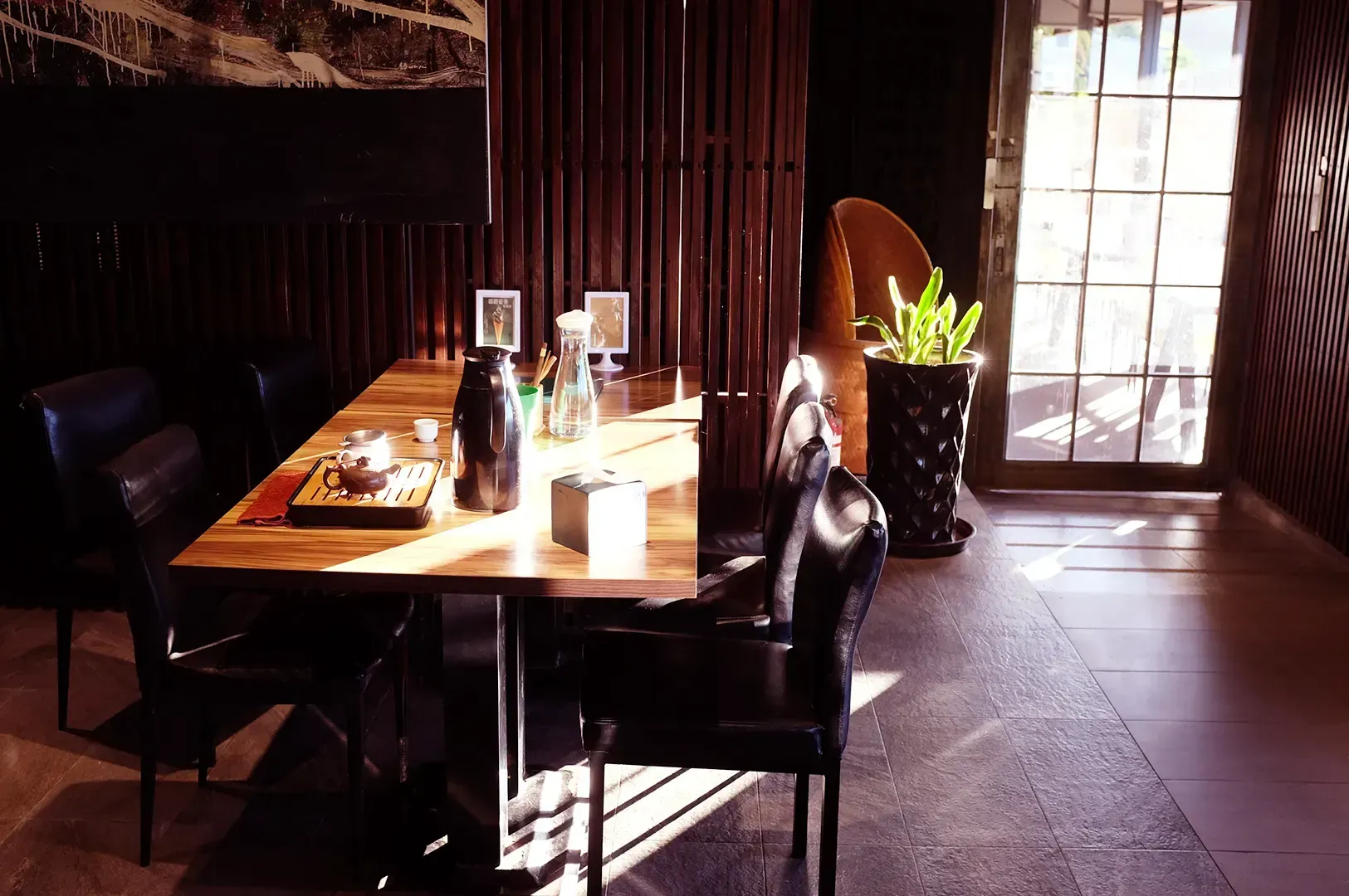 Sunlight streams into a serene tea room, highlighting a wooden table set with a traditional tea serv