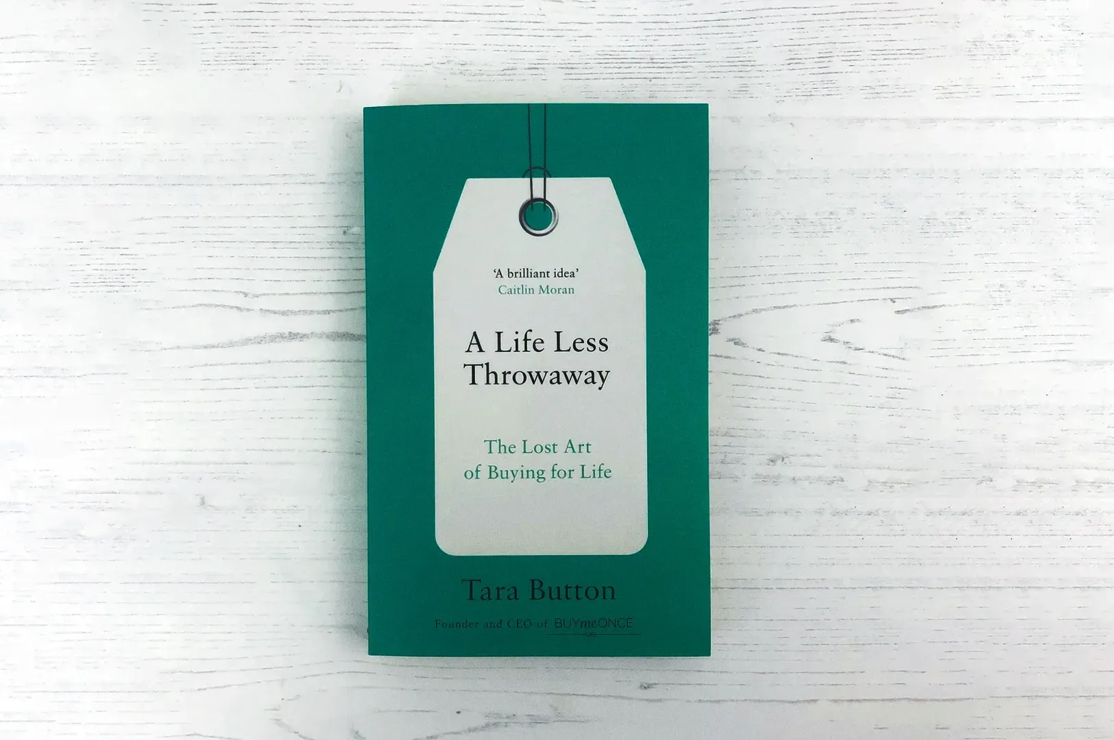 Flat lay overhead shot of “A Life Less Throwaway” by Tara Button on a white wooden surface, minimali