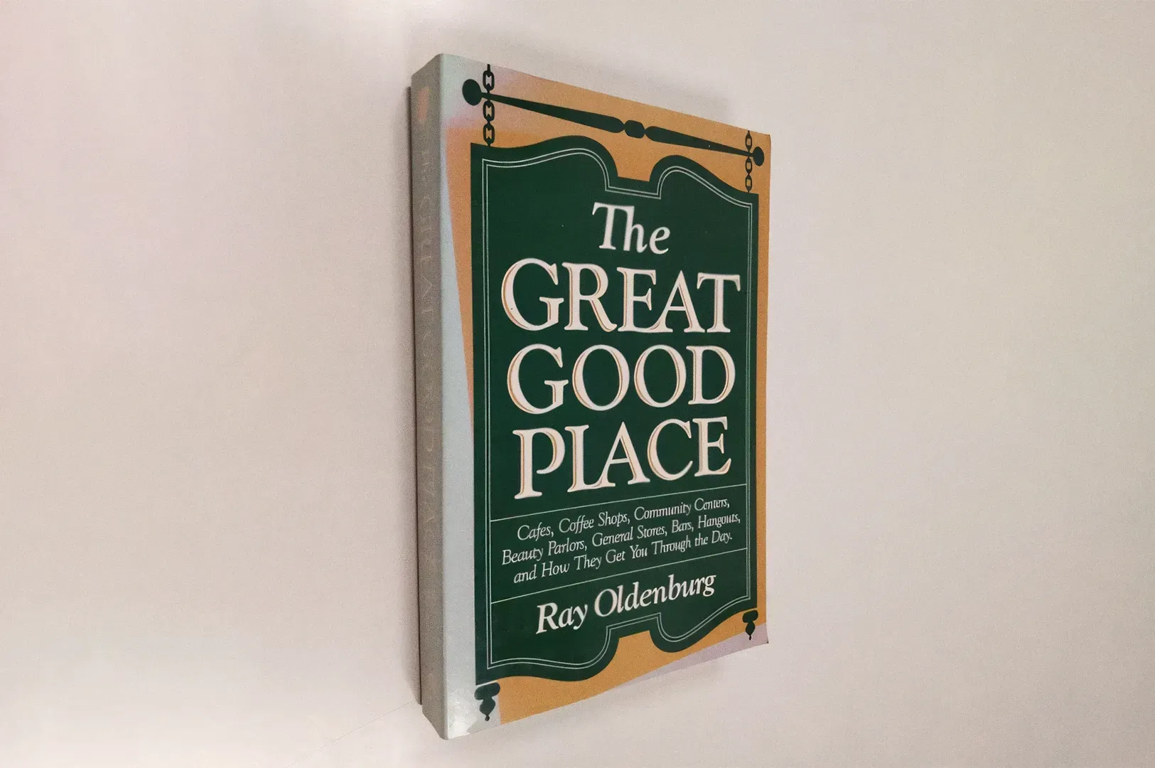 Wall‑mounted copy of “The Great Good Place” by Ray Oldenburg displayed against a minimalist white wa