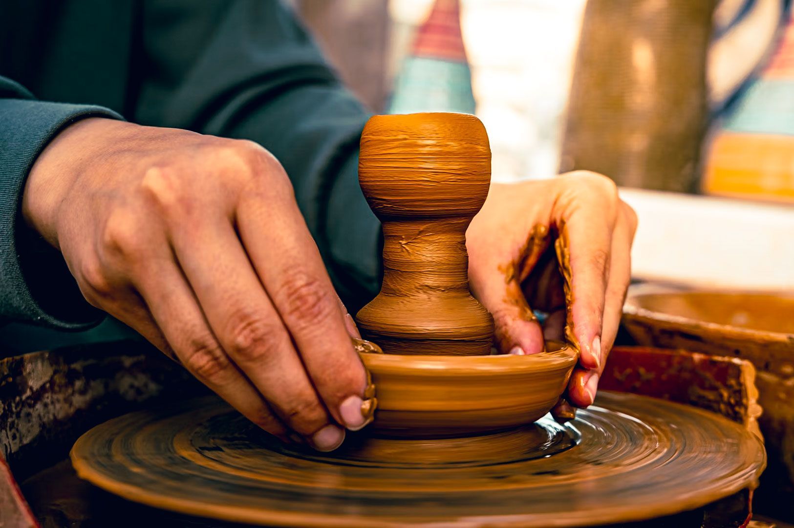 Close-up of hands molding a clay pot on a spinning pottery wheel, showcasing traditional craftsmansh