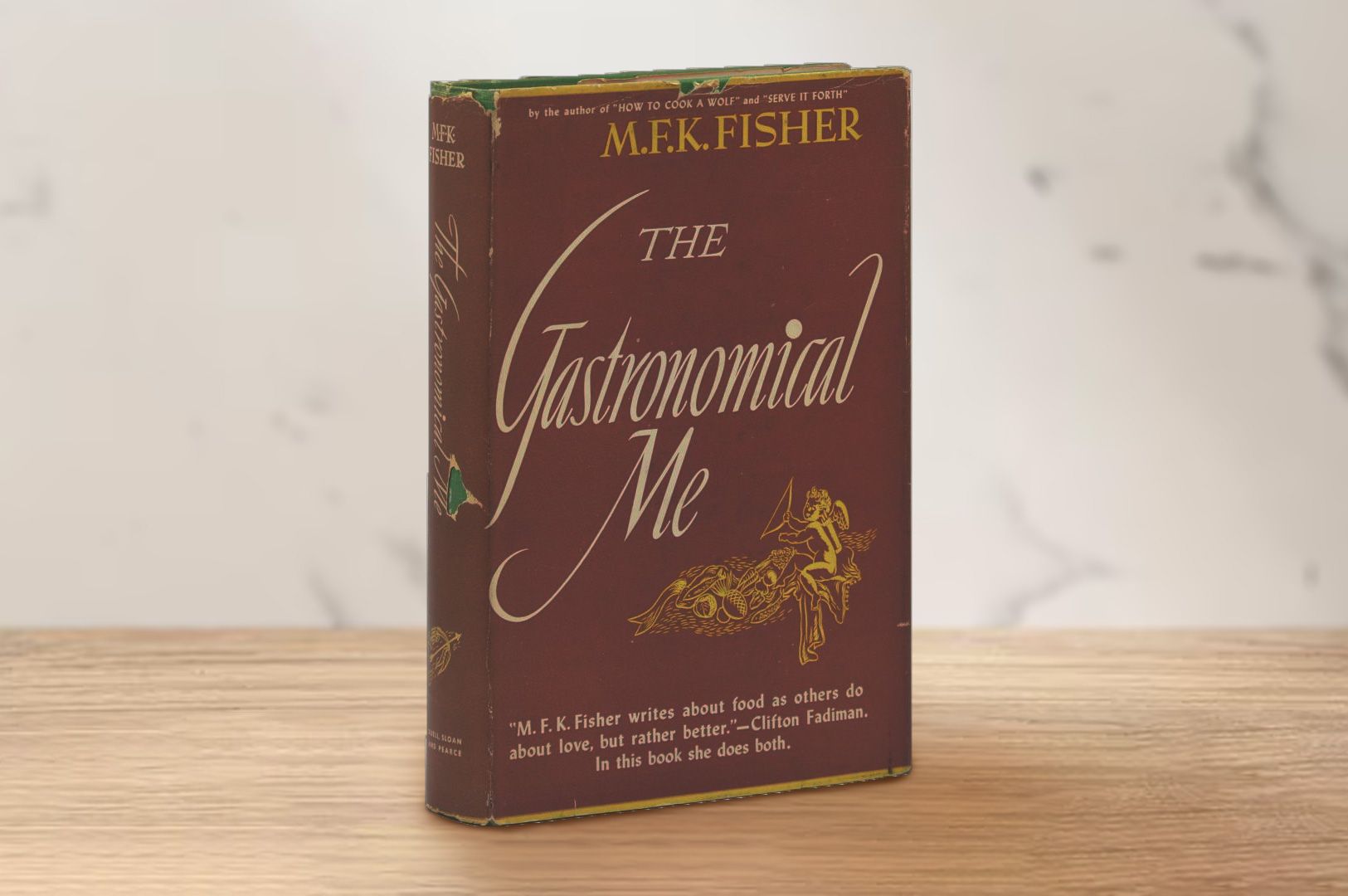 Vintage copy of ‘The Gastronomical Me’ by M.F.K. Fisher standing upright on a wooden surface with a