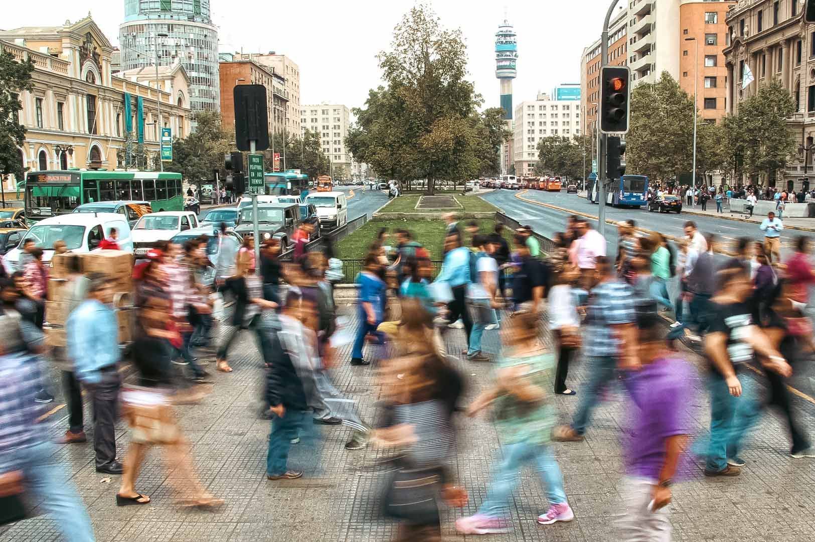 Busy city crosswalk filled with people moving across an urban street.