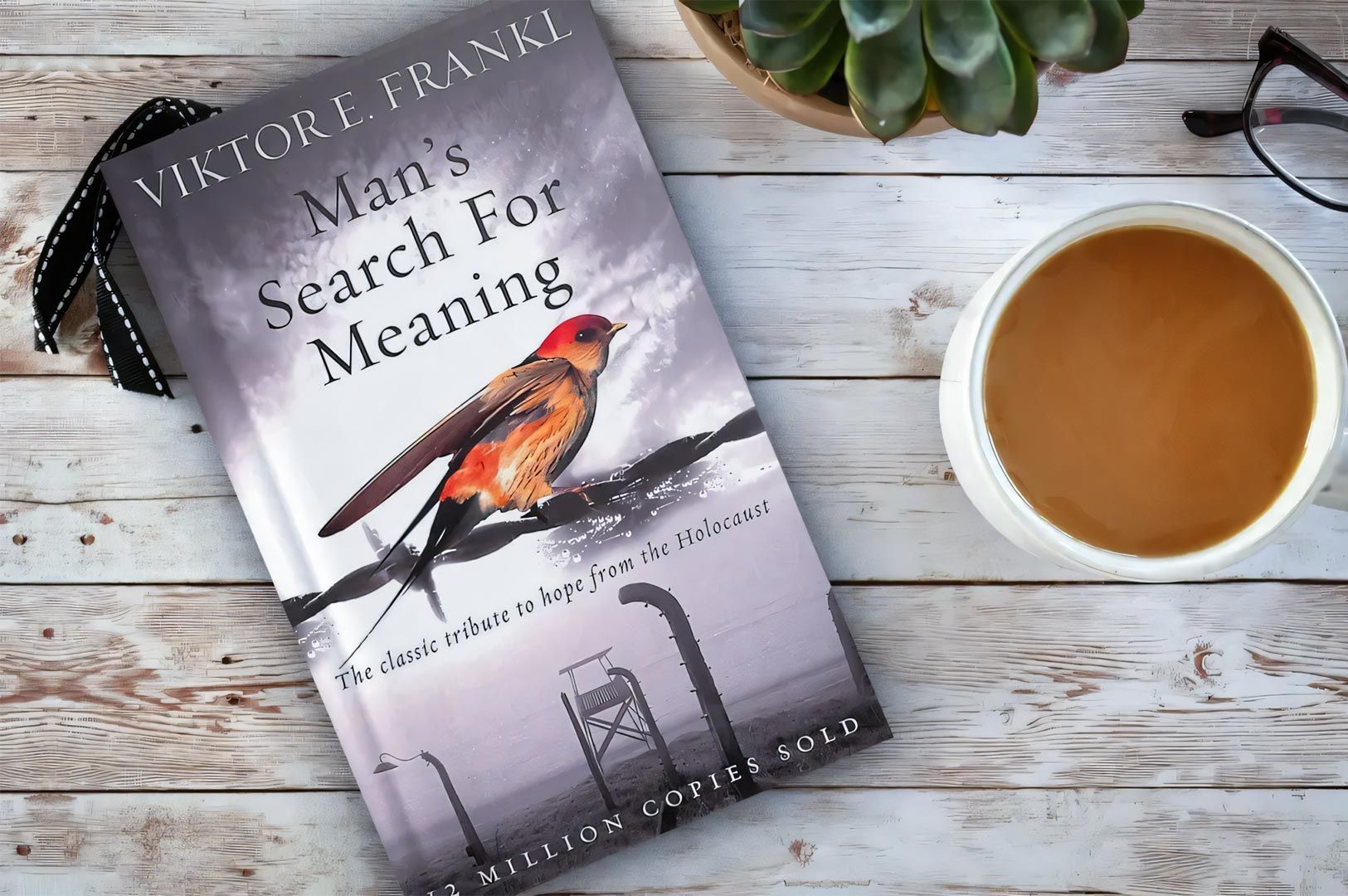 Cover of Viktor Frankl’s book ‘Man’s Search for Meaning’ placed on a wooden table beside a cup of co