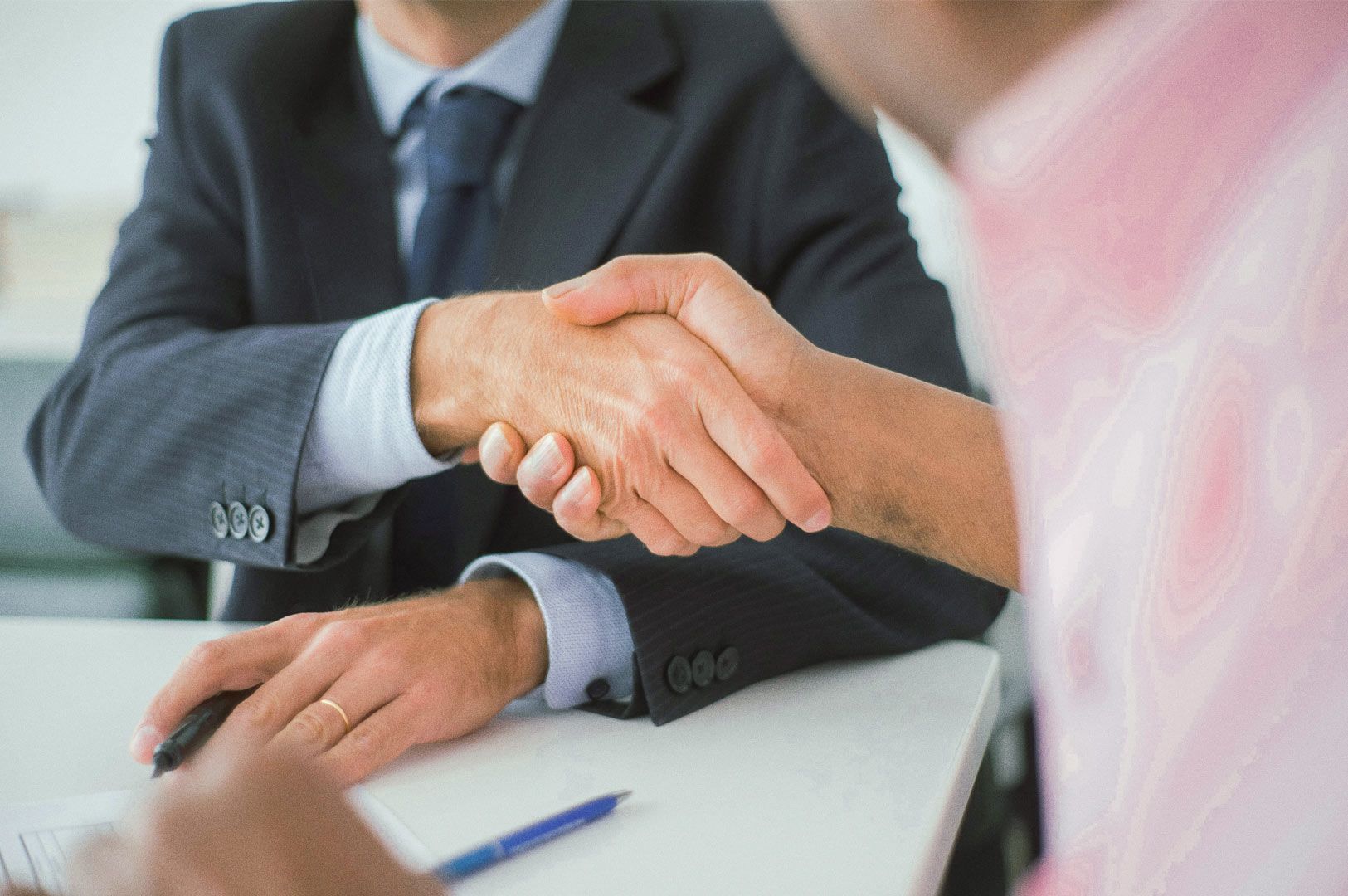 Close-up of two professionals shaking hands across a desk, symbolizing partnership, agreement, or su