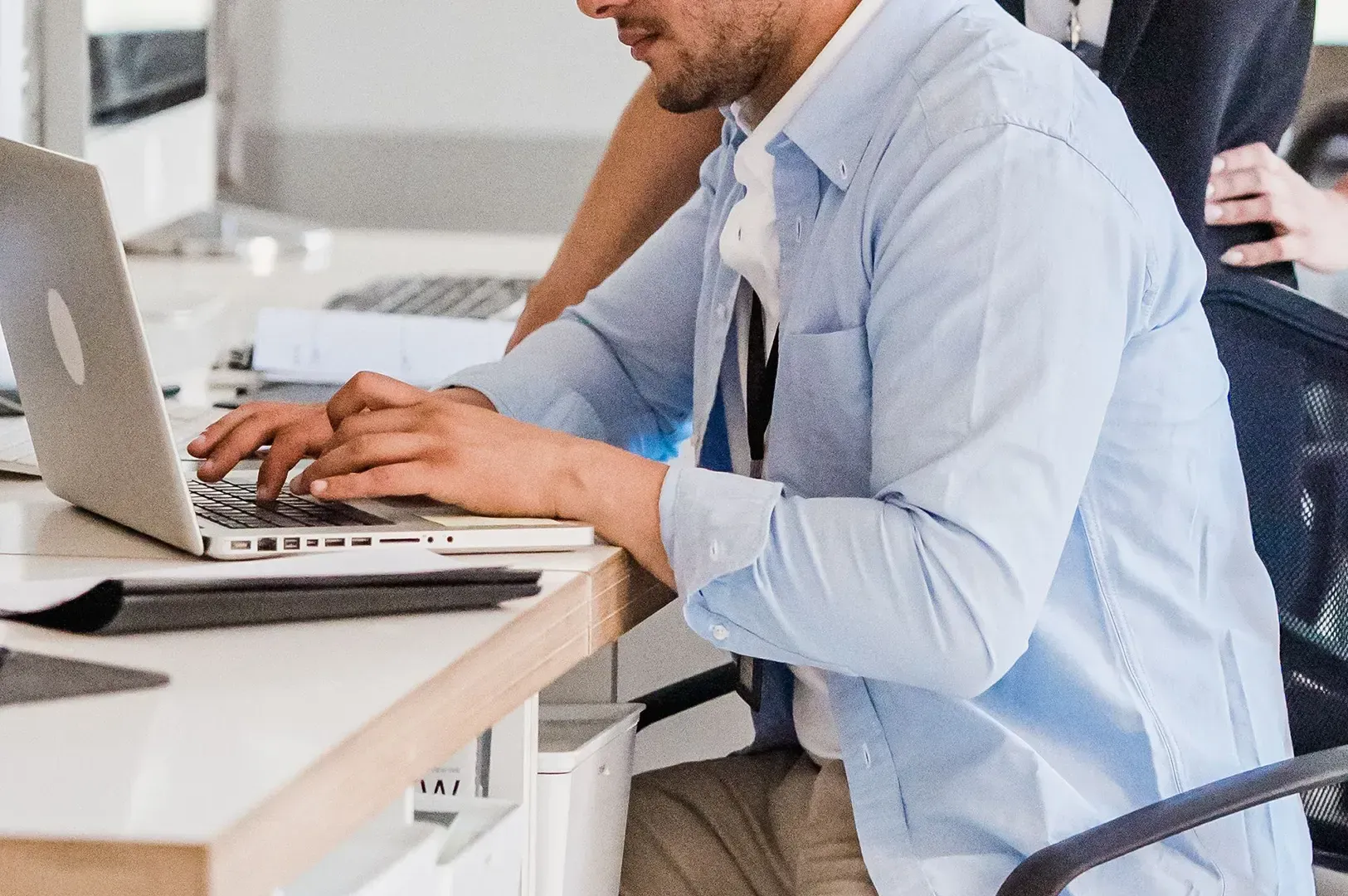A close-up of a professional working on a laptop, symbolizing how teams can apply suspension of judgment and deep listening to foster more meaningful collaboration in modern workplaces.